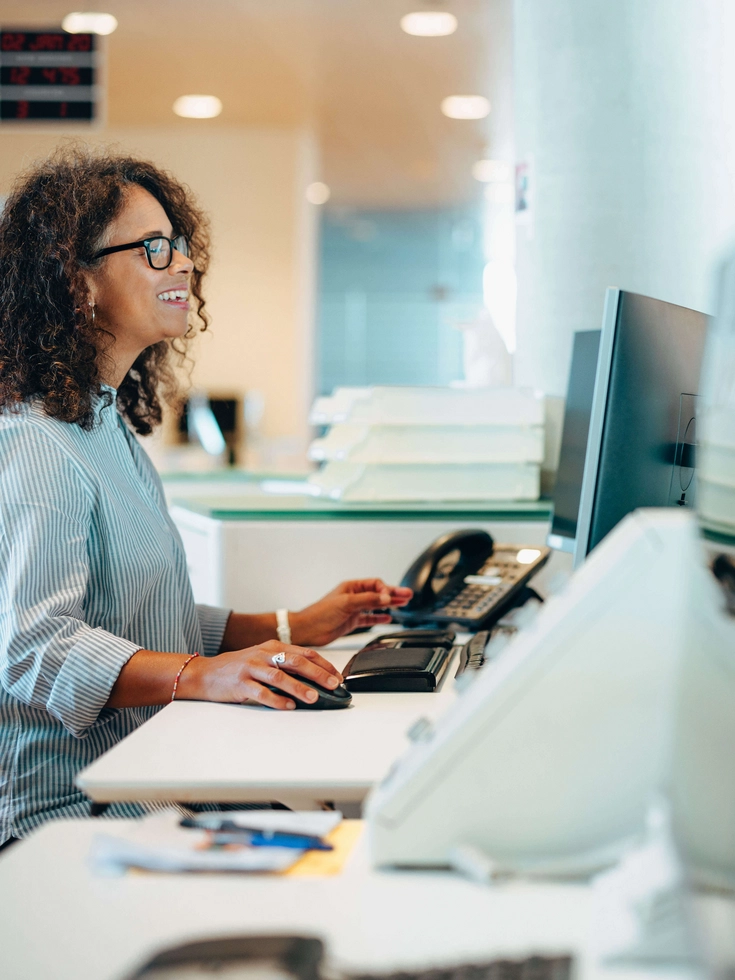 Moderne Bürgerberatung am Empfang Mitarbeiterin am Serviceschalter spricht lächelnd mit einer Besucherin in einem modernen Büro.