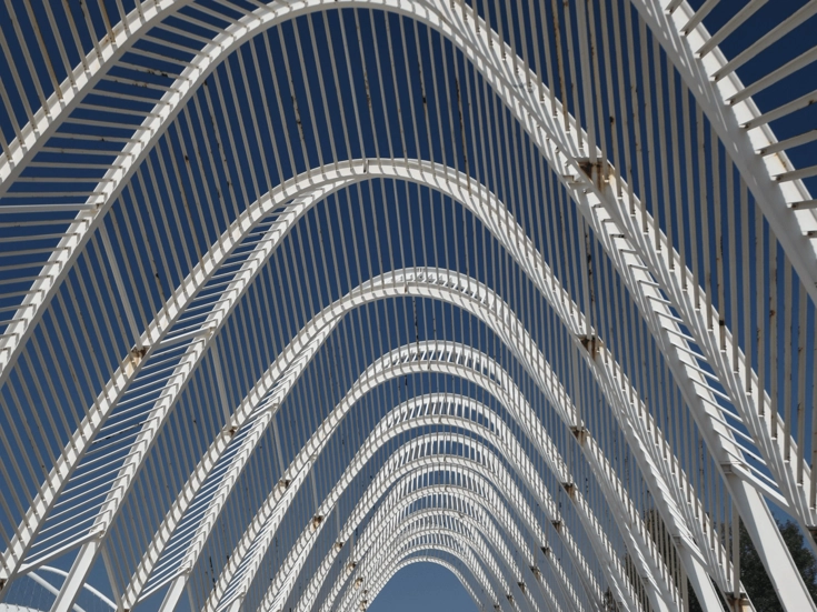 Athen – Olympisches Architektursymbol Blick auf die moderne weiße Bogenkonstruktion des Olympiageländes in Athen vor blauem Himmel.