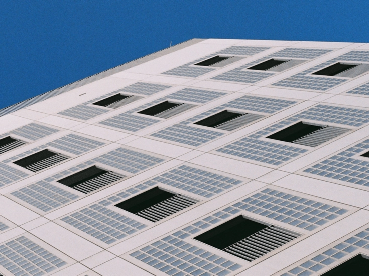 Stuttgart – Modernes Hochhaus Fassadenausschnitt eines modernen weißen Hochhauses mit quadratischen Fensterstrukturen vor blauem Himmel.